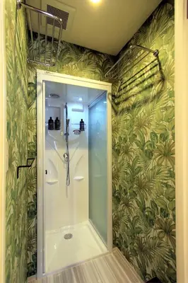 a shower stall in a bathroom with green wallpaper at Sumida-ku - House / Vacation STAY 80877 in Tokyo