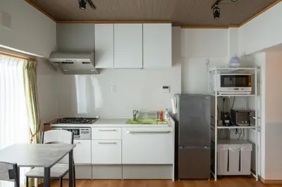 a small kitchen with white cabinets and a table and a refrigerator at NIYS apartments 04 type in Tokyo