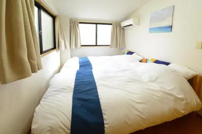 a bedroom with a large white bed with blue stripes at Sumida-ku - House / Vacation STAY 80342 in Tokyo