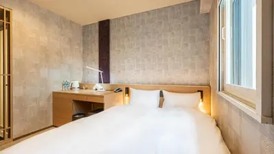 a bedroom with a bed and a desk and a window at Galois Hotel Shinokubo in Tokyo