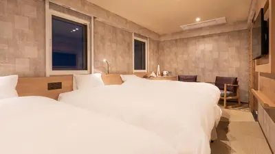 a bedroom with two white beds and a television at Galois Hotel Shinokubo in Tokyo