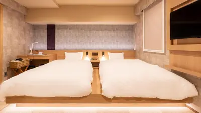 two twin beds in a room with a television at Galois Hotel Shinokubo in Tokyo