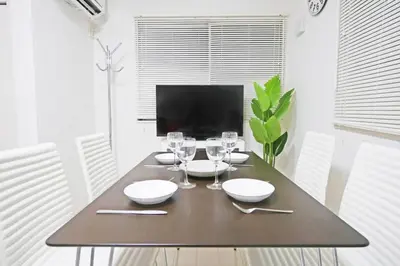 a dining room table with wine glasses and a television at \u30a2\u30f3\u30c9\u30b9\u30c6\u30a4\u9ad8\u78022\u4e01\u76ee in Tokyo