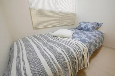 a bedroom with a bed with blue and white sheets at \u30a2\u30f3\u30c9\u30b9\u30c6\u30a4\u9ad8\u78022\u4e01\u76ee in Tokyo