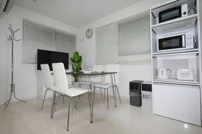 a kitchen with a dining table and white chairs at \u30a2\u30f3\u30c9\u30b9\u30c6\u30a4\u9ad8\u78022\u4e01\u76ee in Tokyo