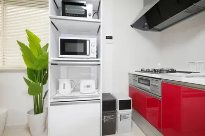 a white kitchen with red cabinets and a microwave at \u30a2\u30f3\u30c9\u30b9\u30c6\u30a4\u9ad8\u78022\u4e01\u76ee in Tokyo