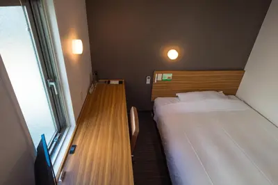a small room with two beds and a window at Super Hotel JR Ueno Iriyaguchi in Tokyo