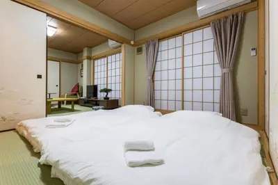 a large white bed in a room with windows at \u30a2\u30f3\u30c9\u30b9\u30c6\u30a4\u6edd\u91ce\u5ddd3\u4e01\u76ee in Tokyo
