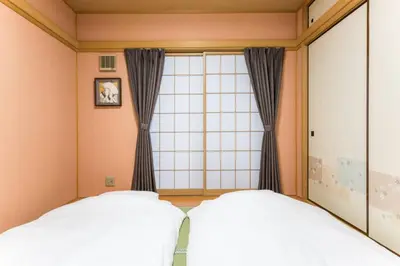 two beds in a room with a window at \u30a2\u30f3\u30c9\u30b9\u30c6\u30a4\u6edd\u91ce\u5ddd3\u4e01\u76ee in Tokyo
