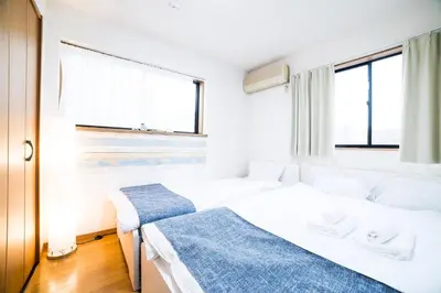 two beds in a room with two windows at \u30a2\u30f3\u30c9\u30b9\u30c6\u30a4\u672c\u753a5\u4e01\u76ee in Tokyo