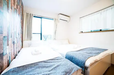 two beds in a room with a window at \u30a2\u30f3\u30c9\u30b9\u30c6\u30a4\u672c\u753a5\u4e01\u76ee in Tokyo
