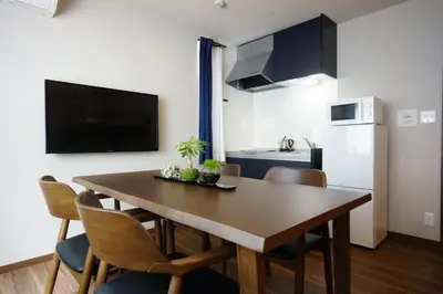 a kitchen with a dining room table with chairs and a refrigerator at RoNa Hotel in Tokyo