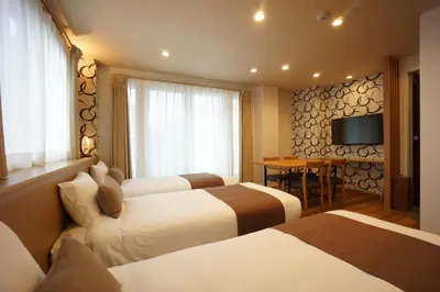 a hotel room with three beds and a television at WIRES HOTEL James zaka in Tokyo