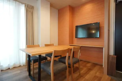 a dining room with a table and a flat screen tv at WIRES HOTEL James zaka in Tokyo
