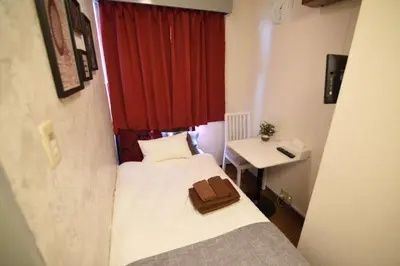 a small room with two beds and a red window at Vail sta Takenotsuka in Tokyo