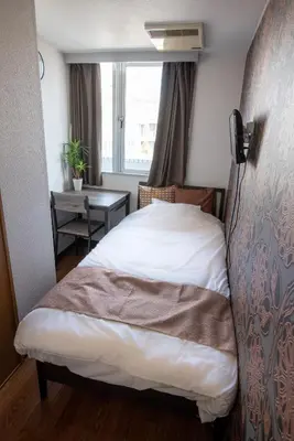 a bedroom with a bed and a window and a table at Vail sta Takenotsuka in Tokyo