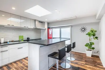 a kitchen with white cabinets and a black counter top at NC Square Shinjuku -All Suite Residence- in Tokyo