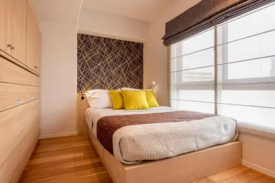 a bedroom with a bed with yellow pillows and a window at NC Square Shinjuku -All Suite Residence- in Tokyo