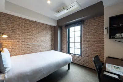 a bedroom with a white bed and a brick wall at HOTEL TABARD TOKYO in Tokyo