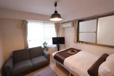 a bedroom with a bed and a couch and a chair at LUANA in BELUBEE in Tokyo