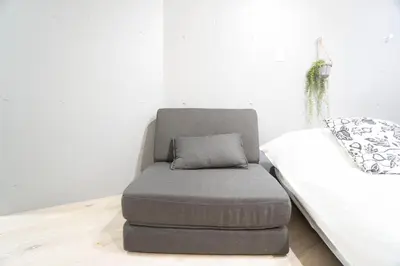 a grey ottoman sitting next to a bed at Hill Side Terrace Hiroo Shibuya 201 in Tokyo
