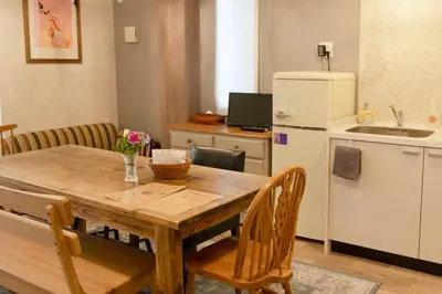 a kitchen with a wooden table and a refrigerator at 7 Rooms Hotel & Cafe - Boutique Designer Hotel - 30 mins from Disneyland&Tokyo in Tokyo