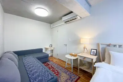 a living room with a blue couch and a bed at Uhome Otsuka Villa in Tokyo