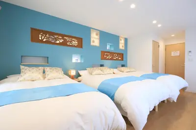 two beds in a room with blue walls at Hikari House in Tokyo