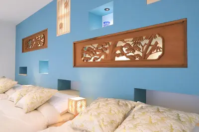 a room with two beds and a blue wall at Hikari House in Tokyo