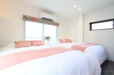 two beds with pink and white sheets in a bedroom at Hikari House in Tokyo