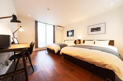 two beds in a room with a desk and a computer at ENGAWA & GIVE Nakano in Tokyo