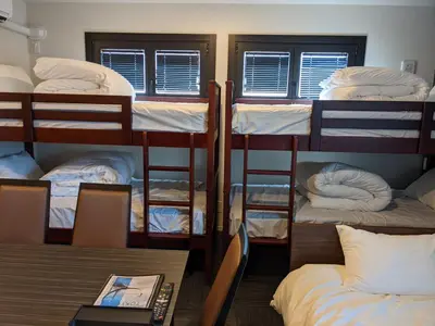 a room with four bunk beds and a table with a laptop at Gennoya in Tokyo
