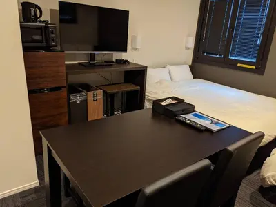 a room with a table with a bed and a television at Gennoya in Tokyo