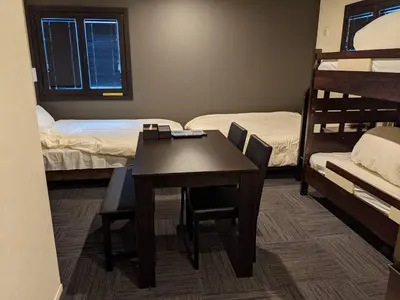 a room with a table and chairs and bunk beds at Gennoya in Tokyo