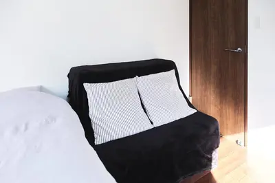 a bed with a black and white pillow on it at Base Hanegi Apartment by Tranova in Tokyo