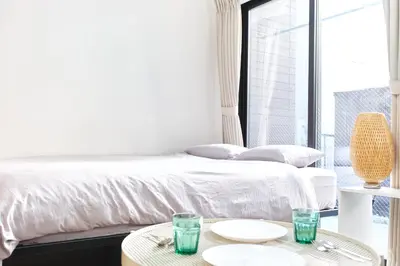 a white bedroom with a bed and two tables at Base Hanegi Apartment by Tranova in Tokyo