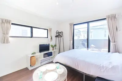 a white bedroom with a bed and a window at Base Hanegi Apartment by Tranova in Tokyo