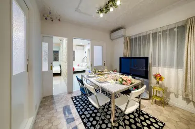 a dining room with a table with chairs and a television at Diamond Moon Palace Takadanobaba,2 stops to Shinjuku in Tokyo