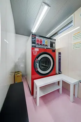 a washing machine sitting in a room with a bench at Diamond Moon Palace Takadanobaba,2 stops to Shinjuku in Tokyo