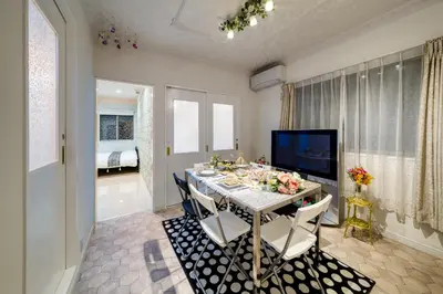 a dining room with a table with chairs and a television at Diamond Moon Palace Takadanobaba,2 stops to Shinjuku in Tokyo
