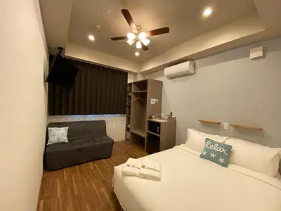 a bedroom with a bed and a couch and a ceiling fan at Kainoa Guesthouse in Tokyo