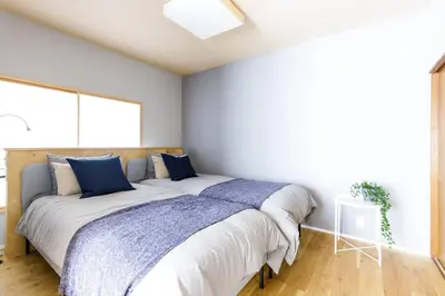 a bedroom with a large bed with blue pillows at NEGAU House in Tokyo