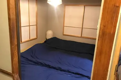 a small bed in a room with two windows at NEGAU House in Tokyo