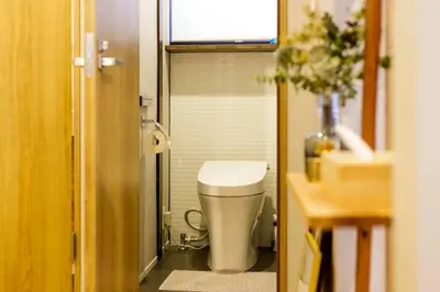 a small bathroom with a toilet and a window at NEGAU House in Tokyo