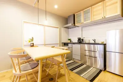 a kitchen with a table and chairs and a refrigerator at NEGAU House in Tokyo