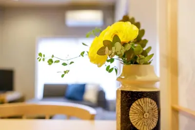 a vase filled with yellow flowers on a table at NEGAU House in Tokyo