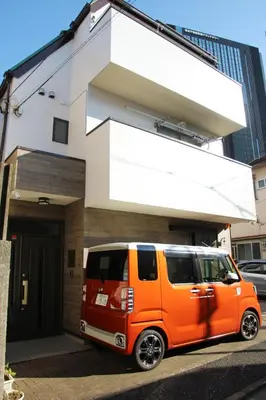 an orange van parked in front of a building at HAMA HILLS Shinjuku in Tokyo