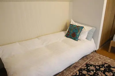 a white bed with a pillow on it in a room at HAMA HILLS Shinjuku in Tokyo