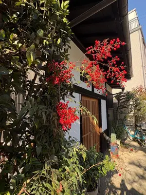 a house with red flowers on the side of it at Kitazawa Cozy House in Tokyo