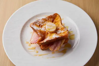 a plate with a piece of toast with ham and syrup at The Gate Hotel Ryogoku by Hulic in Tokyo
